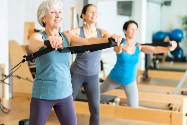 Toning Arms After 60: Empowering Womens Fitness Through Effective Weight Training 2 older woman doing weight training Hamilton and resistance in the gym to tone upper arms